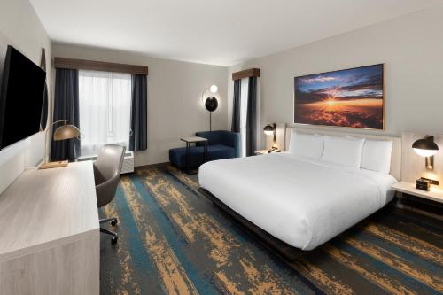a hotel room with a white bed and a television at La Quinta Inn & Suites by Wyndham DeSoto in DeSoto