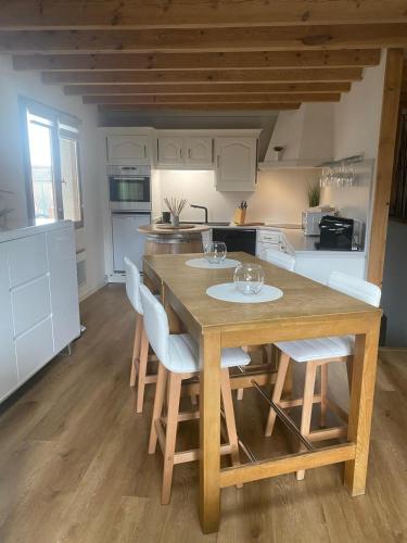 une cuisine avec une table en bois et des armoires blanches dans l'établissement Maison chaleureuse, à Matemale