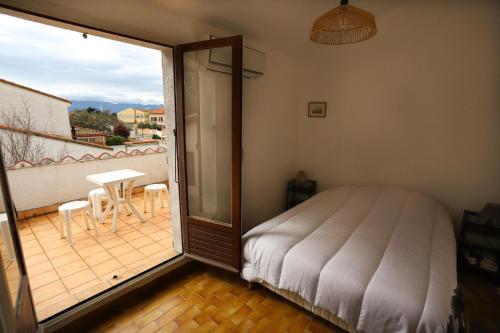 une chambre avec un lit et un balcon avec une table dans l'établissement St Cyprien grande maison familiale proche plage, à Saint-Cyprien