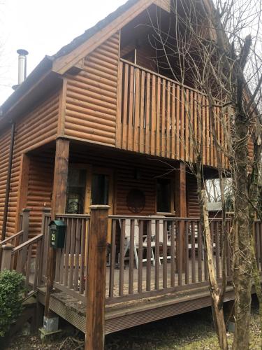 a log cabin with a porch and a fence at Cat's Cabin by the River in Belturbet