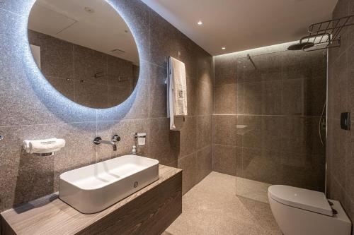 a bathroom with a sink and a toilet and a mirror at Old Theatre Suites - Tremiti in Valletta