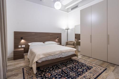 a white bedroom with a large bed and a rug at Old Theatre Suites - Tremiti in Valletta