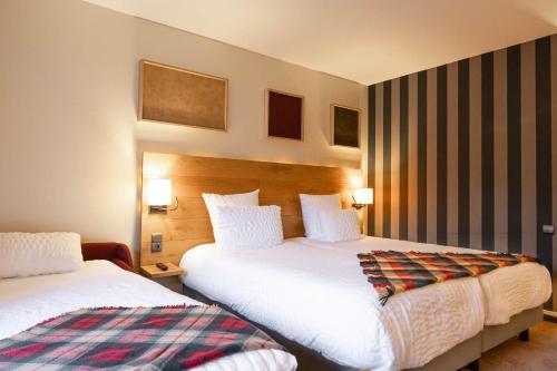 a hotel room with two beds and two lamps at Mercure Saint-Lary in Saint-Lary-Soulan