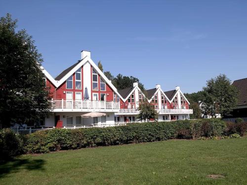 a large red house with a porch and a lawn at Ferienpark Bad Saarow in Bad Saarow
