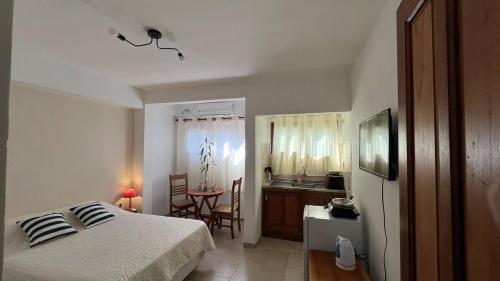 a bedroom with a bed and a table and a kitchen at Pequeño Monoambiente Céntrico IGR 1D in Puerto Iguazú