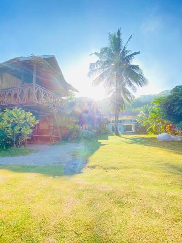 a house with a palm tree in front of it at Ocam Ocam Casadyan Inn in New Busuanga