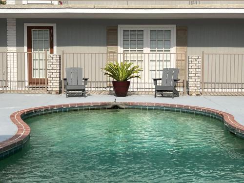 a swimming pool in front of a house with two chairs at 2 br washer dryer Near LSU Tiger Stadium in Baton Rouge