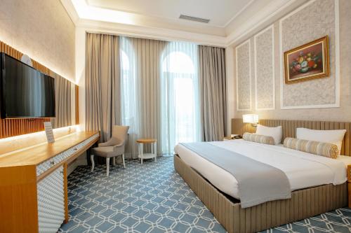 a hotel room with a large bed and a television at Promenade Hotel Baku in Baku