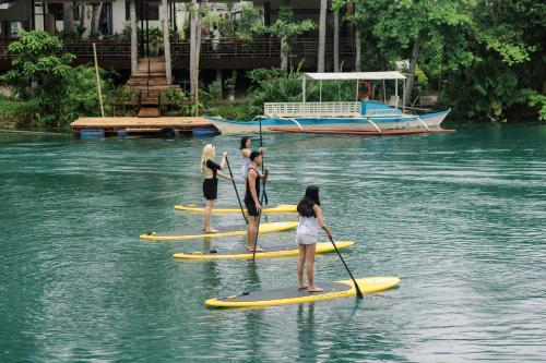 a group of people on paddle boards in the water at Loboc Riverside Inn & Restaurant in Loboc