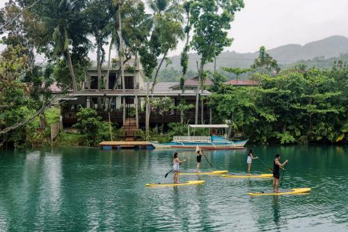 a group of people on paddle boards in the water at Loboc Riverside Inn & Restaurant in Loboc