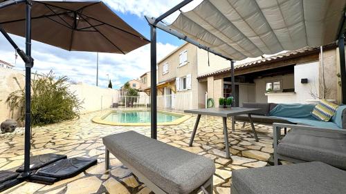 une terrasse avec une table, un parasol et une piscine dans l'établissement Villa Elegance - Piscine - Jardin - Moderne TopProsConciergerie, à Fabrègues