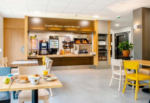 un restaurant avec des tables, des chaises et un comptoir dans l'établissement B&B HOTEL Nantes Savenay, à Savenay