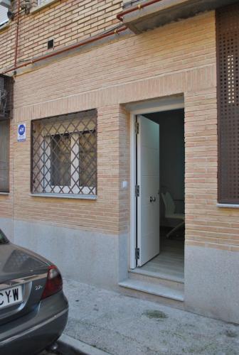 a door to a house with a car parked outside at Viviendas de Uso Turístico Noble Hidalgo TOLEDO in Toledo