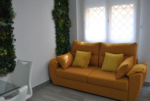 a brown couch with yellow pillows in a living room at Viviendas de Uso Turístico Noble Hidalgo TOLEDO in Toledo