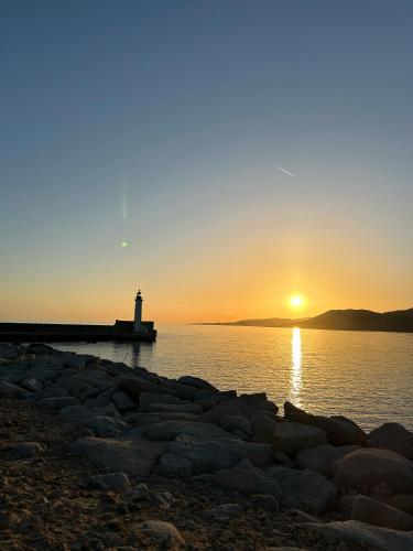 a lighthouse on the water with the sun setting at Residence D Été in Propriano