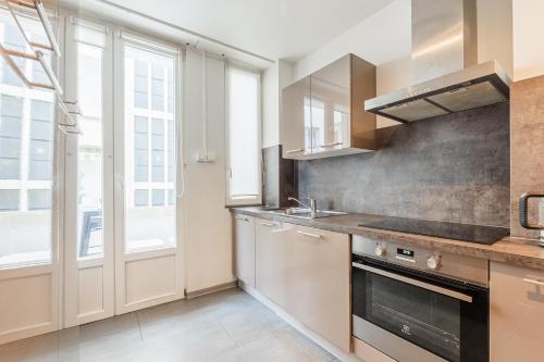 une cuisine avec un évier et une cuisinière dans l'établissement Le Kléber - Appt en hypercentre, proche Place Kléber, à Strasbourg