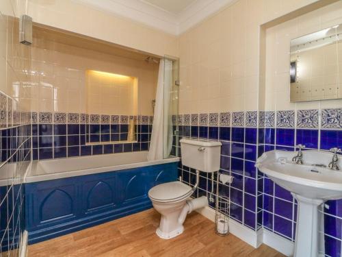 Un baño con azulejos azules, inodoro y lavabo. en Bayview Tower, en Lynton