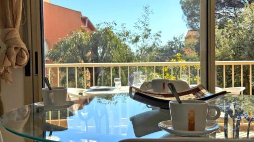 une table en verre avec des tasses à café au sommet d'un balcon dans l'établissement Bosquets, à Sainte-Maxime