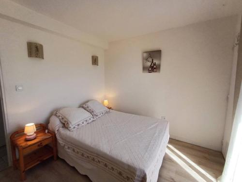 - une chambre avec un lit et une table avec deux lampes dans l'établissement T2 2 étoiles, parking privé, proche Thermes et étang, clim, Wi-Fi, animaux acceptés - FR-1-571-15, à Balaruc-les-Bains