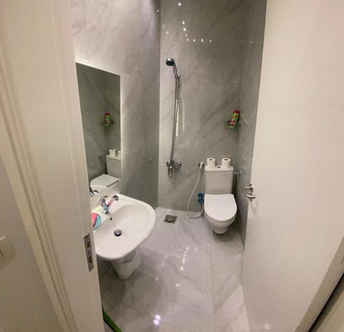 a white bathroom with a toilet and a sink at Nile Inn 503 Cozy Studio Steps Away From the Nile in Cairo