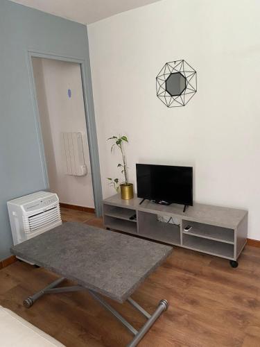 a living room with a tv and a table at OTA T2 proche rivières et plages, randonnées in Guaita