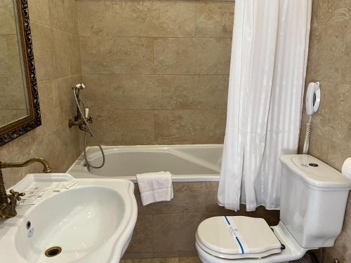 a bathroom with a sink and a toilet and a tub at Royal Grand Hotel in Kyiv