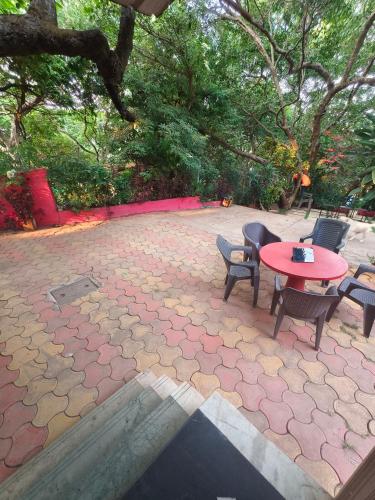 a patio with a table and chairs and trees at Girichintan Bunglow in Mahabaleshwar