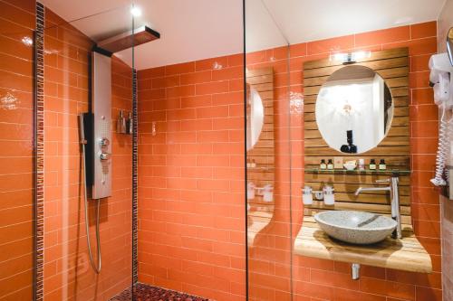 an orange tiled bathroom with a sink and a shower at Le Palais d'Aglaé, Hôtel de Charme in Gordes