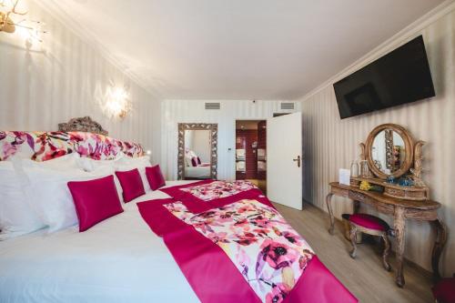 a bedroom with a large bed with pink and white sheets at Le Palais d'Aglaé, Hôtel de Charme in Gordes