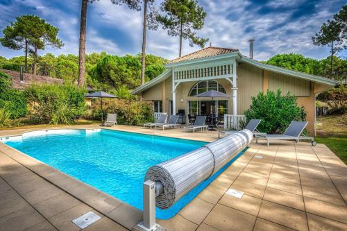 une piscine avec toboggan en face d'une maison dans l'établissement Villa élégante à Lacanau + piscine, à Lacanau