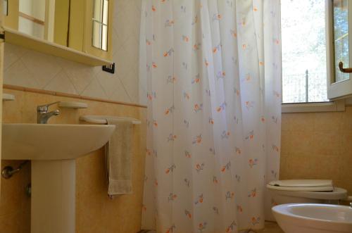a bathroom with a sink and a shower curtain at Padula Bianca - villa con accesso privato per la spiaggia in Rivabella