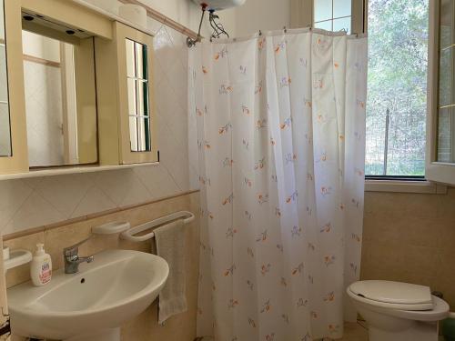 a bathroom with a sink and a shower curtain at Padula Bianca - villa con accesso privato per la spiaggia in Rivabella