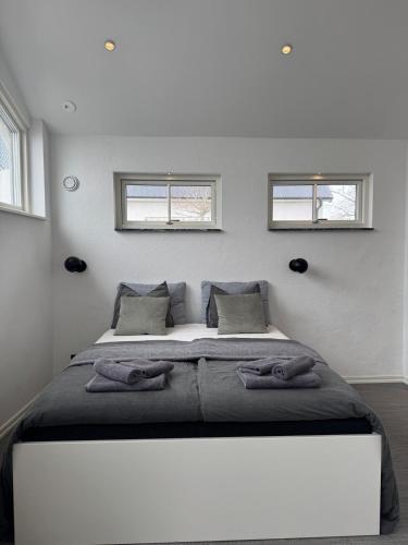 a bedroom with a large bed with two windows at Lilla huset på Norregårda in Hammenhög