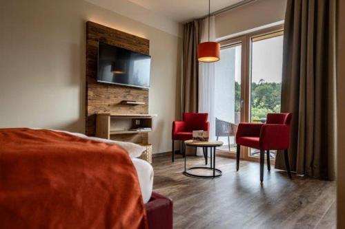 1 dormitorio con sillas rojas y sala de estar. en Triad Gästehaus DZ, en Krumbach Markt