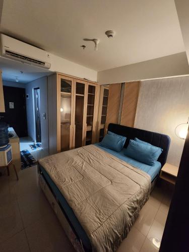 a bedroom with a bed with blue pillows on it at Cozy Studio Apartement South Surabaya in Surabaya