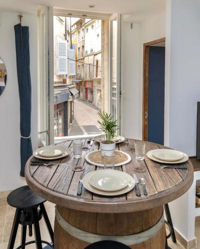 - une table en bois avec des assiettes dans une chambre avec une fenêtre dans l'établissement Suite Bleu d'Azur - Hypercentre - Wifi, à Apt