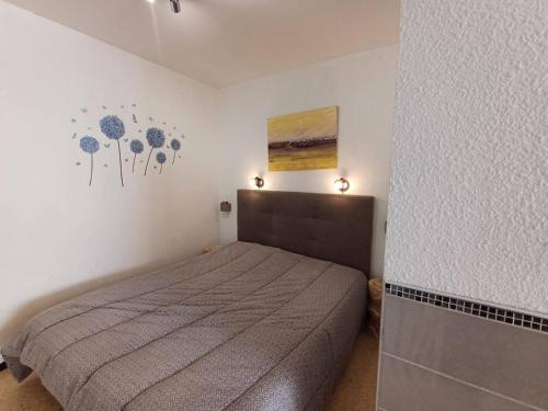 une chambre avec un lit et un tableau au mur dans l'établissement T1 cosy à Balaruc-les-Bains avec clim, terrasse et animaux admis - FR-1-571-59, à Balaruc-les-Bains