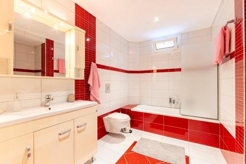 a red and white bathroom with a toilet and a sink at Celeste Sea View Apartment Hot Tub 18 plus Adults only in Psalidi