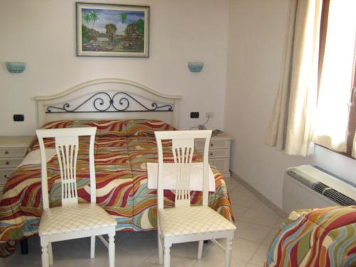 a bedroom with a bed and two chairs at Scano Comfort Inn in Santa Teresa Gallura