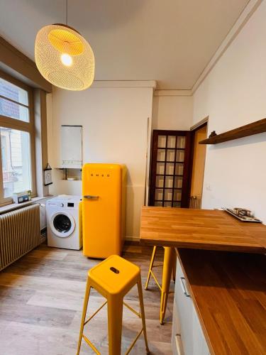 Il comprend une cuisine équipée d'un réfrigérateur jaune, d'une table et d'un tabouret. dans l'établissement Duplex du Palais, à Douai