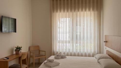 een slaapkamer met een bed, een bureau en een raam bij Estelle in Bari