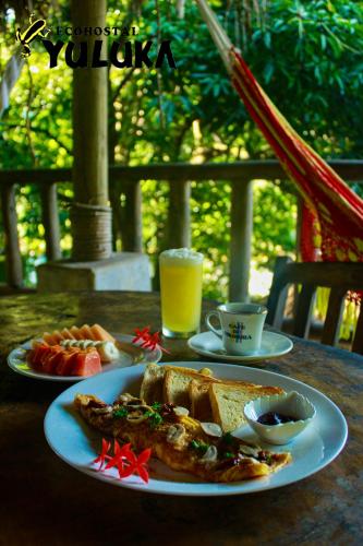 a table with two plates of food and a glass of orange juice at Eco Hostal Yuluka in El Zaino