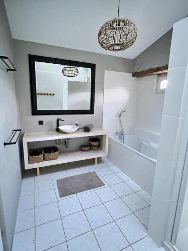 une salle de bain avec un lavabo, une baignoire et un miroir dans l'établissement Gîte Rochellier - Charente-Maritime, à Cravans