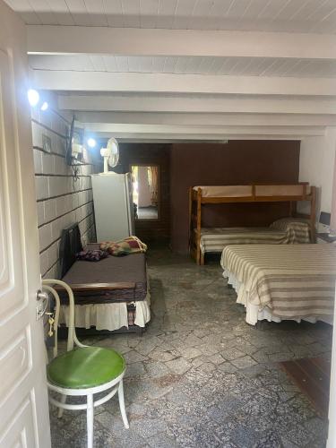 a room with two beds and a green chair at Monoambientes CDM in Capilla del Monte