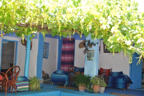 a porch with chairs and tables and a tree at Ferme Dar Aicha green Bellouta in Bellouta