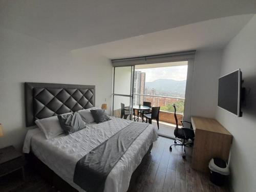 a bedroom with a bed and a desk and a window at Amplio apartamento con vista campestre in Sabaneta
