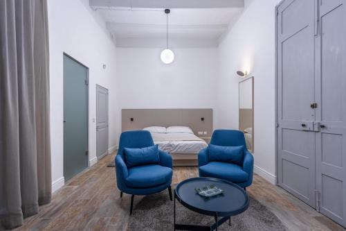 a bedroom with two blue chairs and a bed at Old Theatre Suites - Vulcano in Valletta