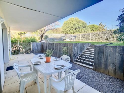 une table blanche et des chaises sur une terrasse dans l'établissement Royal Rivage - Piscine - Mer à 200m, à Carqueiranne