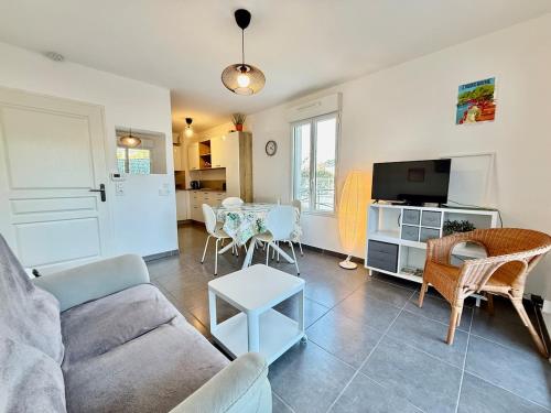un salon avec un canapé et une table avec des chaises dans l'établissement Royal Rivage - Piscine - Mer à 200m, à Carqueiranne