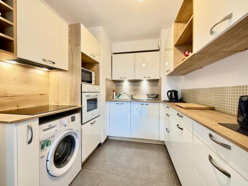 une cuisine avec des armoires blanches et une laveuse et une sécheuse dans l'établissement Royal Rivage - Piscine - Mer à 200m, à Carqueiranne